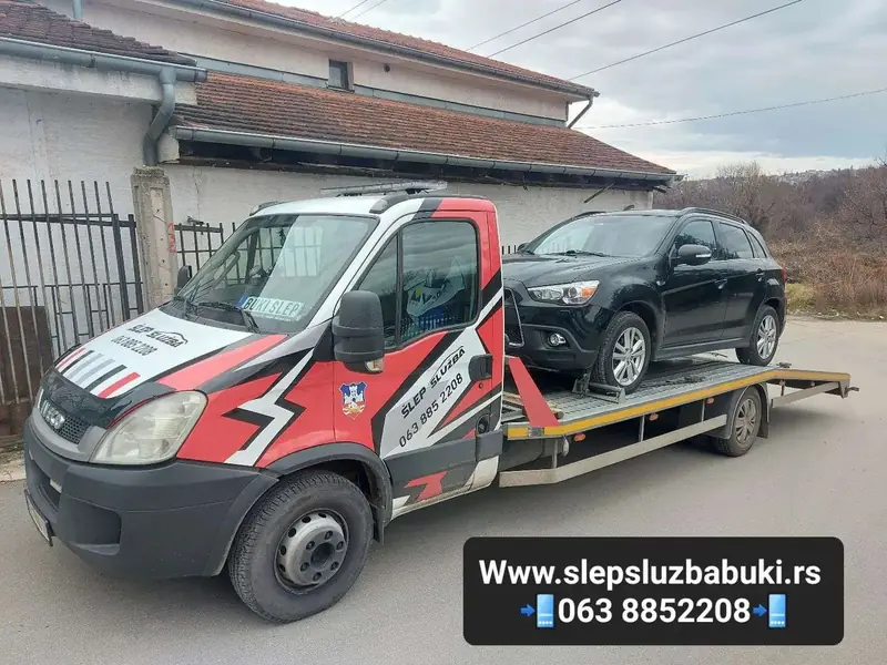 Crni SUV utovaren na šlep vozilo ispred stambene kuće